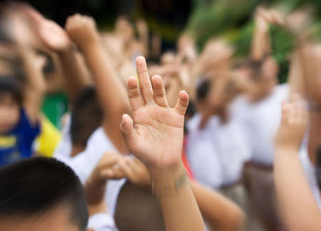 sharp hand raised in blury schoolyard background zooming inの写真素材