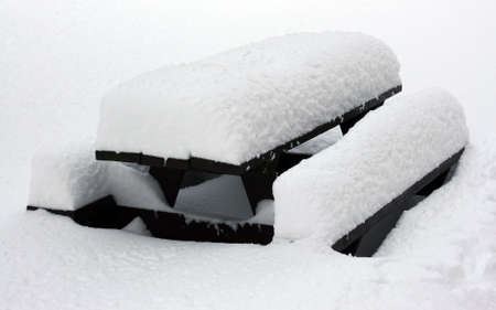 picnic table covered with inches of snow の写真素材