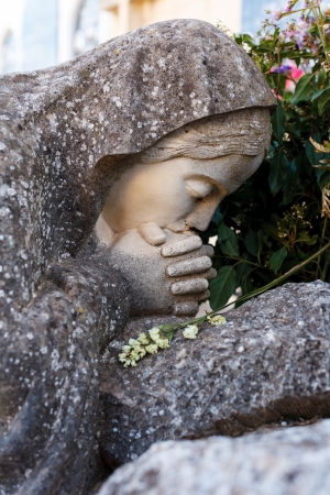 Praying virgin stone in the cemetery on a graveの写真素材