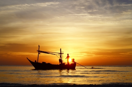 Silhouette of fisherman on boat in the sunrise, Hua Hin, Thailandの写真素材