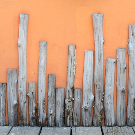 Log wood decorated on orange cement wall in public gardenの写真素材