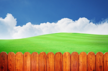 Beautiful green field  with blue sky, white cloud and vintage wooden fenceの写真素材