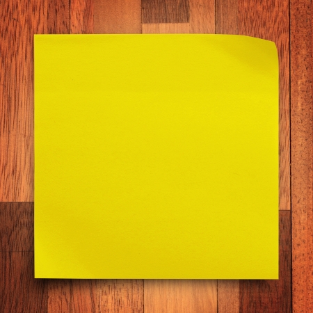 Yellow sticker paper note on wood wall backgroundの写真素材