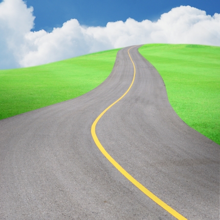 Long road with beautiful green grass field and blue sky, abstract background.の写真素材