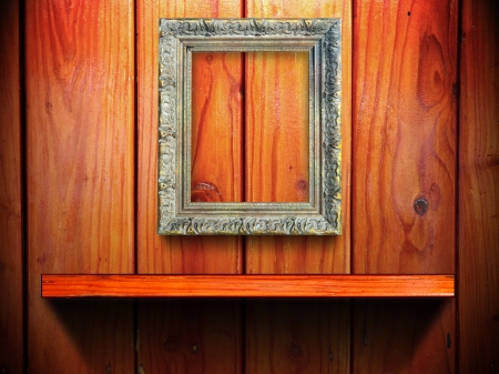 Classic golden frame on wood wall and shelf with light and shadowの写真素材