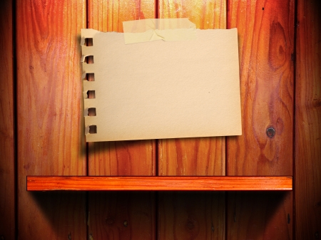 Empty torn paper note on wood wall and shelf with light and shadowの写真素材