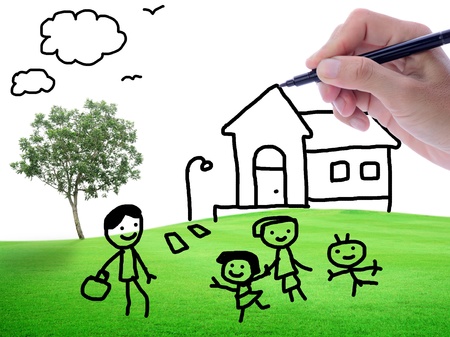 Man's hand sketching house and family on green field backgroundの写真素材