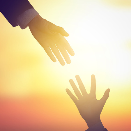 Business man giving helping hand, warm tone background, retro filter with vintage style and glow light effect. Business concept in helping, supporting, partnership or rescue. の写真素材