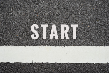 Top view of message START on asphalt road with white dividing stripes. Business concept in start or...