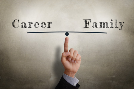 Businessman hand point at balance between  Career and Family. Glow light efffect, vignette and shadow on concrete wall background.の写真素材