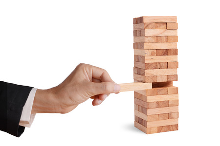 Business man hand pick and put last piece block of the wood puzzle, abstract business concept of last important solution in strategy.の写真素材