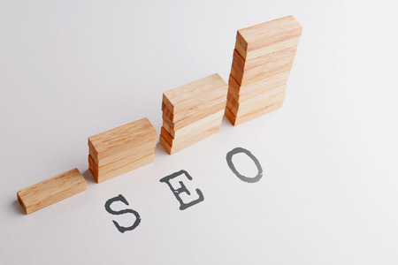Stack of wood block in statistics graph shape with text SEO, abbreviation of Search, Engine, Optimization. Business concept in rising and growing SEO. Selective focus, gray background.の写真素材