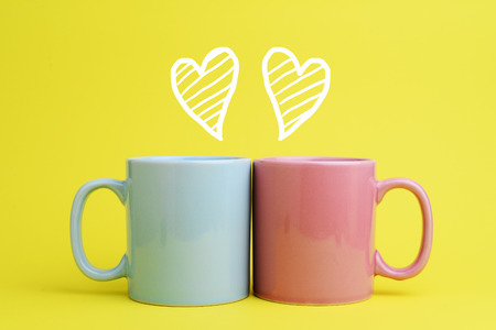 Two blue and pink coffee cup put next to each other with sketching of heart shape in romantic concept. Side view. の写真素材