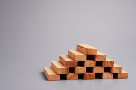 Wood block step stair in shape of pyramid on gray background. Selective focus. Blank and empty space for your text or design.の写真素材