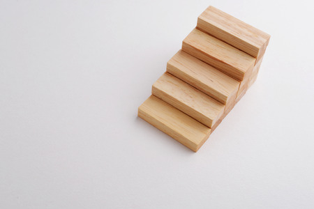 Wood block shape in step stair, selective focus on down stair, gray background with copyspace. Business concept in growing, development, or raising economy. の写真素材