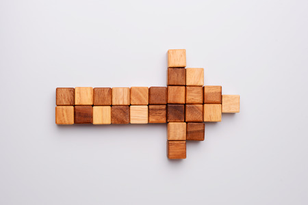 Cube or square wood block in shape of arrow to right side, business concept about direction, top view on gray background. の写真素材