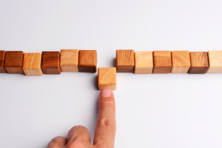Man finger put last cube wood block to complete and finish wood block in line, symbolizing joining team or making unity teamwork, successful, or completion.   の写真素材
