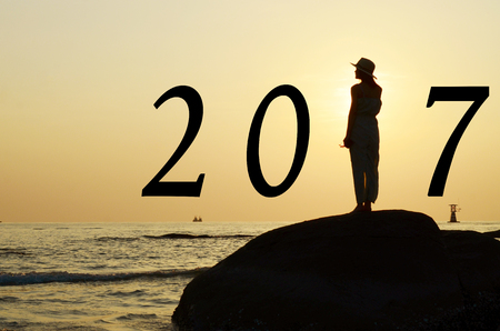 Beautiful asian woman standing on stone silhouetted the sunrise in morning scene with year 2017 calendar.の写真素材