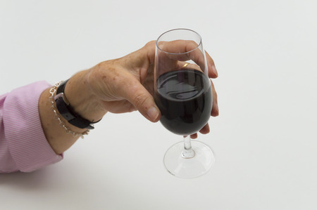 Old woman hand holding a glass of wineの写真素材