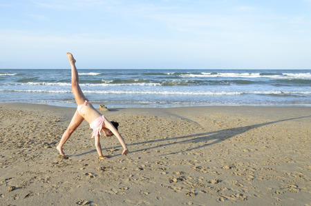 Young caucasian woman doing cartwheel on the beachの写真素材