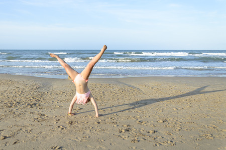 Young caucasian woman doing cartwheel on the beachの写真素材