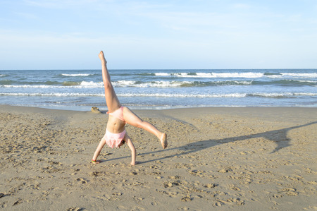 Young caucasian woman doing cartwheel on the beachの写真素材