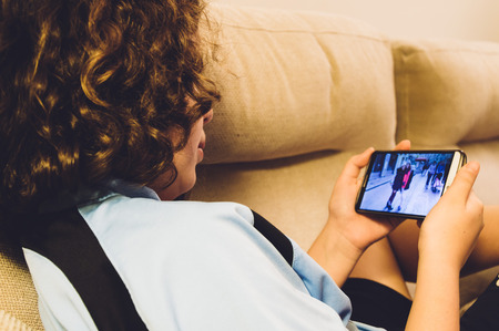 Girl sitting at home using her smartphoneの写真素材