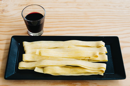 Fresh pasta and red wine on wooden tableの写真素材