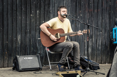 LONDON, UK - AUGUST 20, 2015: Street musician plays acoustic guitar near at Camden Town Market....