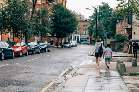 LONDON, UK - AUGUST 23, 2015: People walking on Swanfield Street a rainy day. Swanfield street is located in Shoreditch, near Brick Lane Market.のeditorial素材