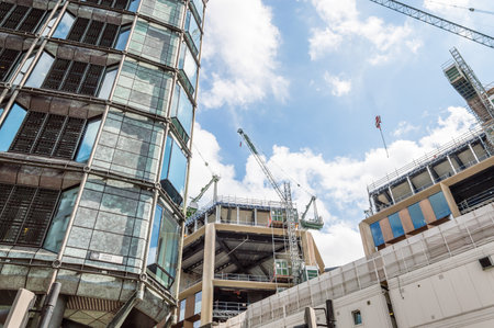 LONDON, UK - AUGUST 21, 2015:  Cranes on a building under construction in London a blue sky day. Low angle viewのeditorial素材