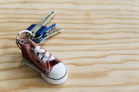 Key chain with little red shoe on wooden backgroundの写真素材