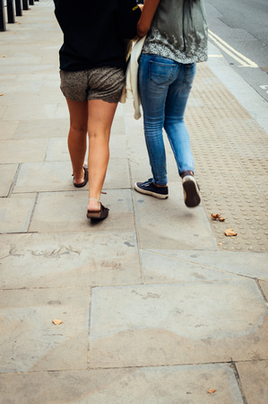 Two young women walking on the street. Only legs, rear viewの写真素材