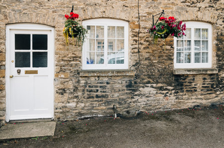 STOW-ON-THE-WOLD, UK - AUGUST 12, 2015:  Limestone cottage entrance. Painted wooden  door and windows decorated with flowers and natural plants.のeditorial素材