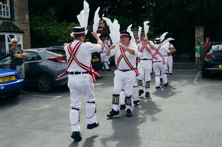 Stow on the Wold, UK - August 12, 2015: Morris Dancers dancing in a square at the village of Stow on the Wold in the Cotswolds, while some tourists are watching them.のeditorial素材