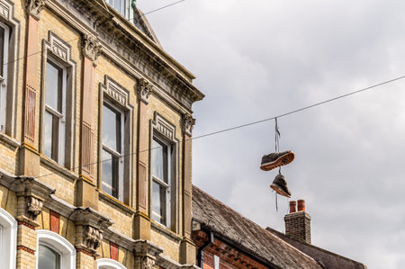 Sneakers hanging on powerlines against the buildings of the city of Winchester, UKのeditorial素材