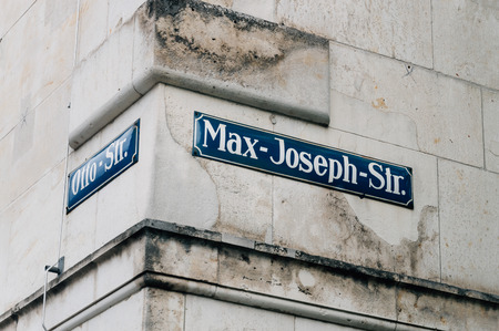 Street name signs in a corner of Munich on a stone wall.の写真素材