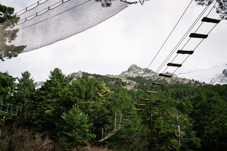 Zip line in woodland against snow capped mountain range. Navacerrada, Madrid, Spain