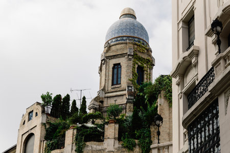 Madrid, Spain - September 18, 2016:   Low angle view of  buildings at Gran Via Street in Madrid. Dome in penthouse against cloudy sky. It is an important street in Central Madrid with shops and theaters.のeditorial素材