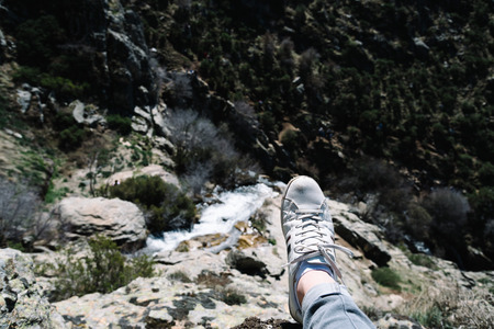 Man wearing sneakers from personal point of view contemplating the beautiful waterfall in mountain landscape in Madrid mountain range. Focus on foregroundの写真素材