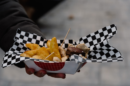 Midsection Of man Holding Street Food with meat and french fries. Focus on foreground
