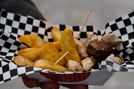 Midsection Of man Holding Street Food with meat and french fries. Focus on foreground