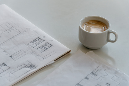 Cup of coffee and architect drawings on deskの写真素材