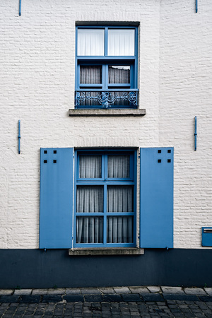 Blue wooden windows and shutters in old building with white painted brick facade in Brugesの写真素材