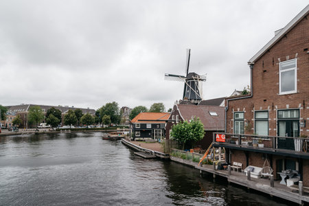 Haarlem, Netherlands - August 3, 2016: Picturesque cityscape with beautiful traditional house, windmill and vessels in canal of Haarlemのeditorial素材