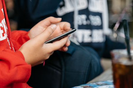 Young woman sitting in the bar texting on phoneの写真素材