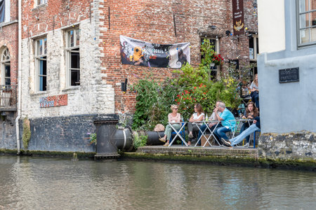 Ghent, Belgium - July 31, 2016: People sitting on a restaurant terrace in Embankment Graslei in the historic center of Ghent with picturesque old buildingsのeditorial素材