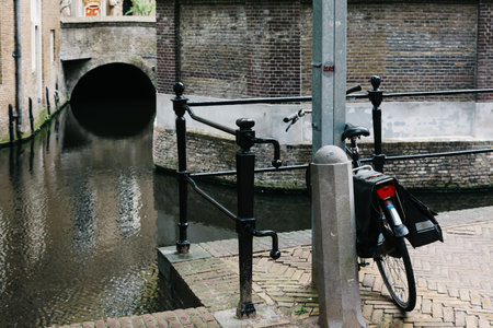 Gouda, Netherlands - August 4, 2016: Bicycle parked by the canal in a picturesque street in the dutch city of Goudaのeditorial素材
