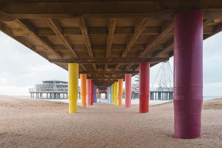 Shot under pier with color painted columns on the beach at sunset.の写真素材