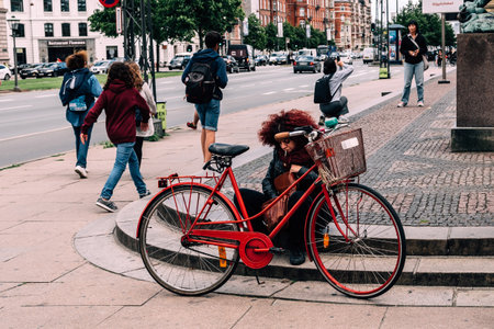 Copenhagen, Denmark - August 10, 2016. Unidentified woman with bicycle smoking at entrance to Ny Carlsberg Glyptotek a blue sky day of summer. It is an art museum built around the personal collection of  the founder of the Carlsberg Breweries.のeditorial素材